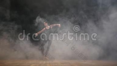 年轻美丽的芭蕾舞演员在烟雾<strong>舞台</strong>上在黑暗中芭蕾在黑暗中。 穿着黑色<strong>服装</strong>的女人在现场<strong>表演</strong>